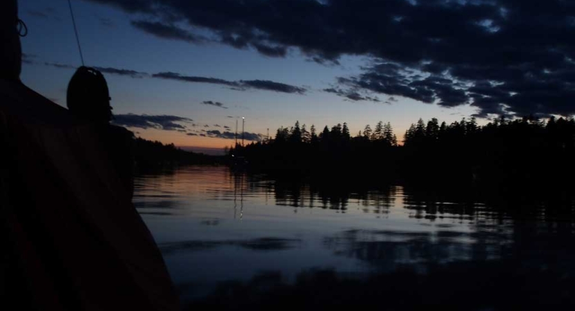 The sky appears in gentle colors above trees and a body of water. 